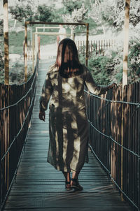 Rear view of woman walking on footbridge