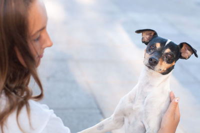 Side view of woman pampering dog on footpath