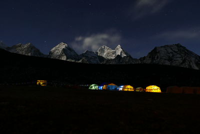 Illuminated tents on mountain against sky at night