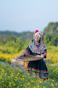 Woman standing on field with yellow flowers in background