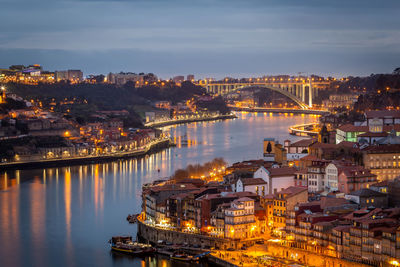 High angle view of illuminated buildings by river against sky