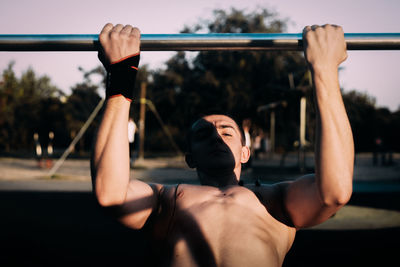 Rear view of shirtless man hanging outdoors