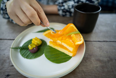 Close-up of hand holding fruits in plate on table