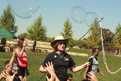 Full length of happy young woman with balloons against trees