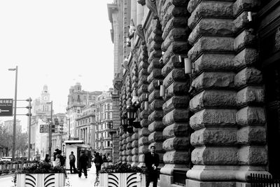 People walking on street in city against clear sky