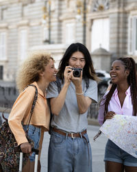 Happy multi ethnic group of tourist friends taking photos of their trip