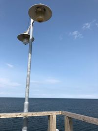 Low angle view of street light by sea against sky