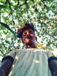 Low angle portrait of young man against tree