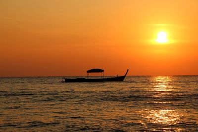 Silhouette boat in sea against orange sky