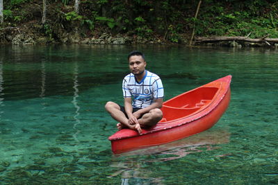 Portrait of man sitting in lake against trees