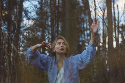 Young woman with short hair dancing against trees in forest