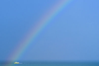 Rainbow over sea against clear blue sky