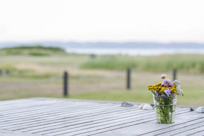 Close-up of flower vase on table against sky