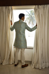 Rear view of man standing at home