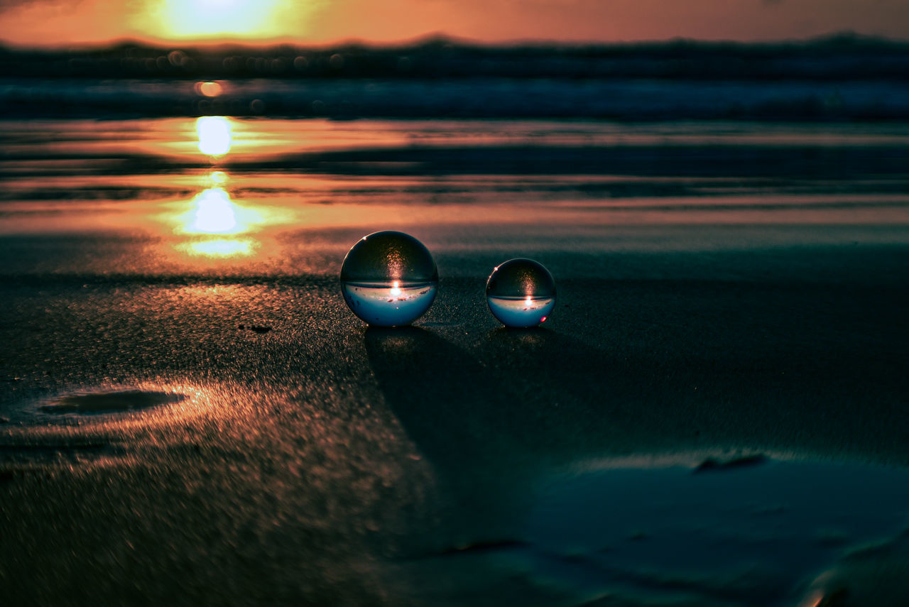 CLOSE-UP OF SUNGLASSES ON BEACH AGAINST SKY