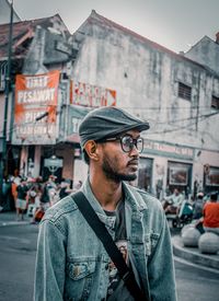 Portrait of young man standing on street in city