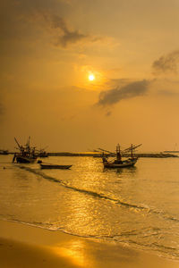 Fishing boat in sea against sky during sunset