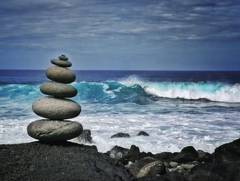 Stack of pebbles on beach against sky