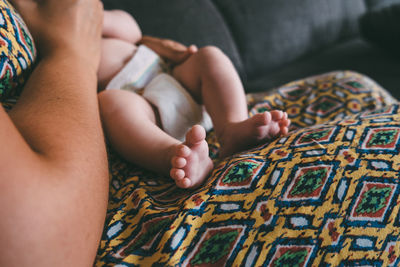 Midsection of woman holding baby on sofa at home