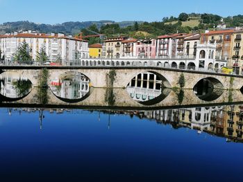 Arch bridge over river against buildings in city