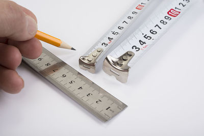 Cropped hand holding thermometer against white background
