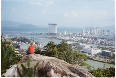 Rear view of woman by cityscape against sky