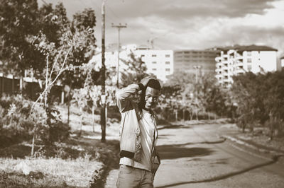 Woman standing by plants against trees