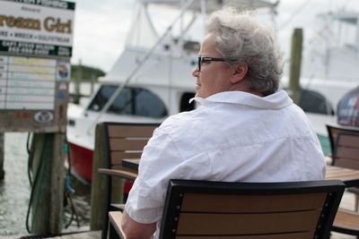 Woman sitting on chair at harbor