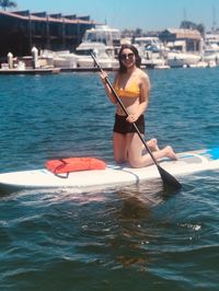 Woman on surfboard rowing in sea