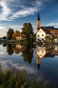 Reflection of trees and buildings in lake against sky