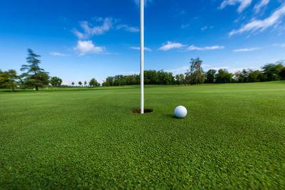 Golf ball on field against sky