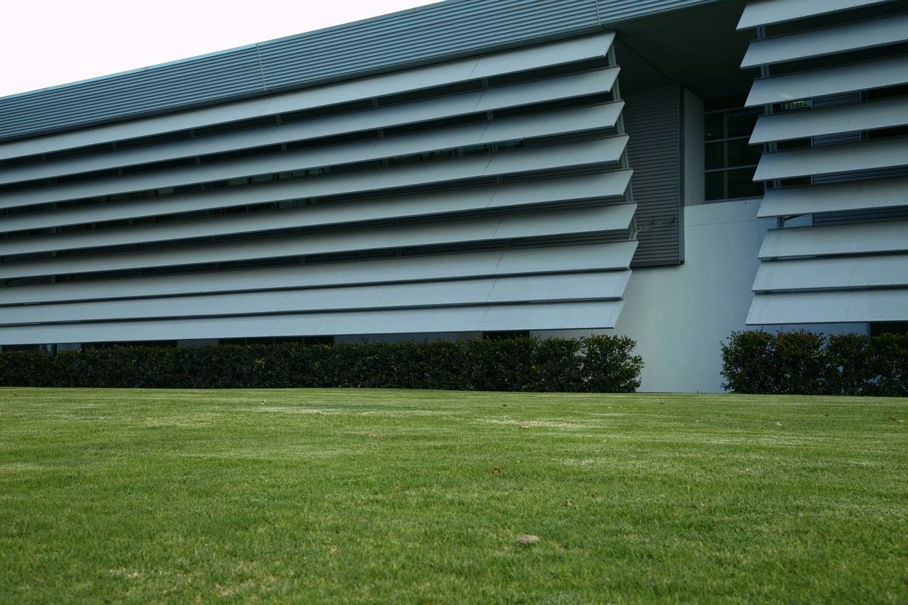 grass, architecture, built structure, building exterior, green color, lawn, growth, grassy, day, building, no people, outdoors, green, sunlight, tree, window, modern, field, sky, plant