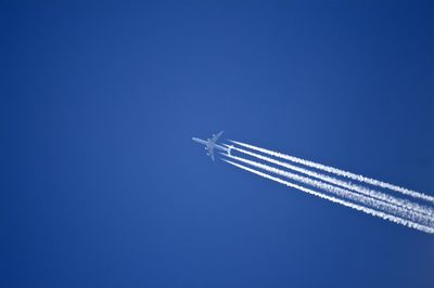 Low angle view of airplane flying against clear blue sky