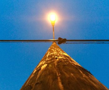 Low angle view of illuminated street light against blue sky