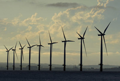 Wind turbines in sea against sky