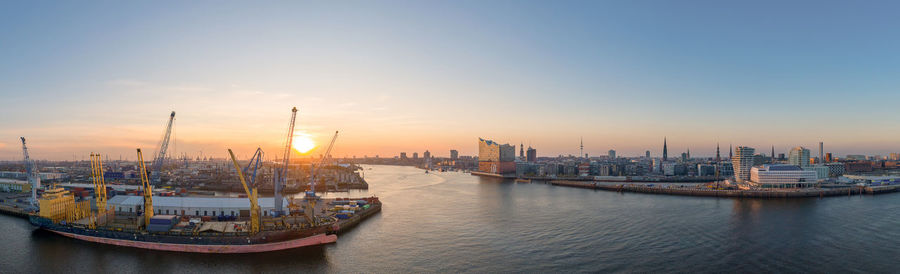 Panoramic view of sea and buildings against sky during sunset