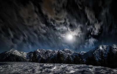 Scenic view of snow covered mountains against dramatic sky