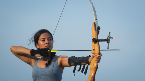 Young woman with arms raised against clear sky