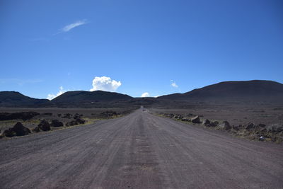 Road amidst desert against blue sky