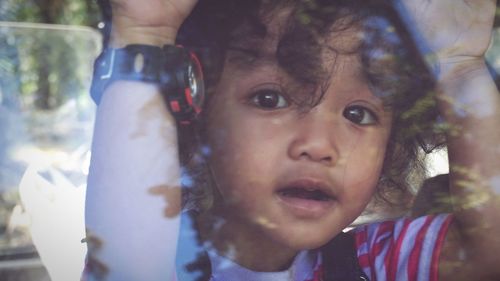 Close-up portrait of cute baby looking through window