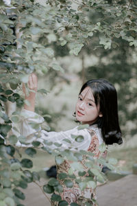 Portrait of young woman standing against trees