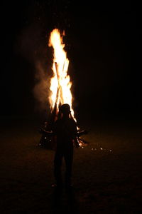 Silhouette person with fire on field at night