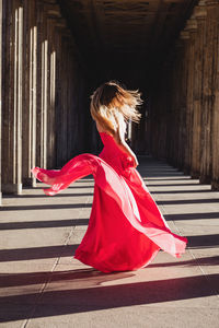 Woman wearing red dress while dancing in corridor