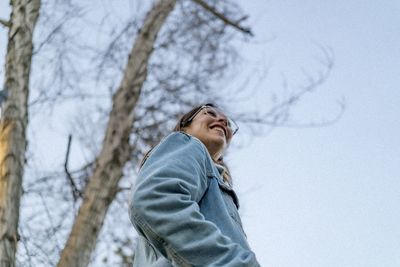 Low angle view of young woman standing against sky