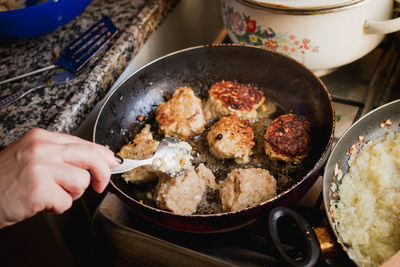 Cropped hand of woman preparing food on stove