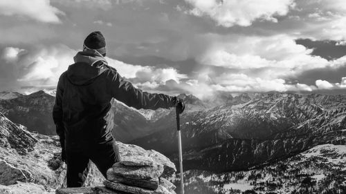 Rear view of man looking at snowcapped mountains against sky