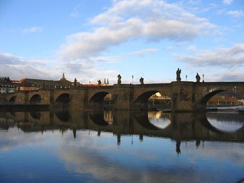 Arch bridge over river against sky in city