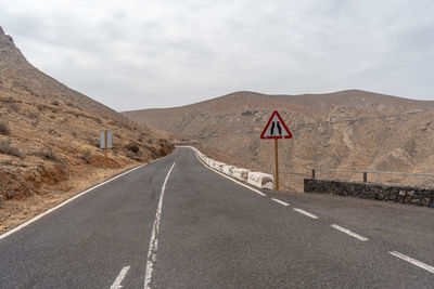 Road leading towards mountain against sky