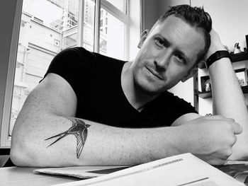 Portrait of young man sitting on table at home