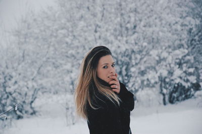 Portrait of beautiful young woman standing in snow during snowfall
